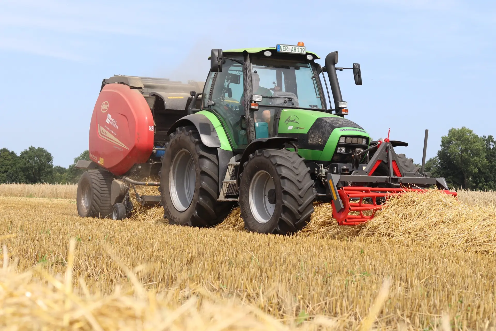 Traktor mit Rundballenpresse auf dem Feld